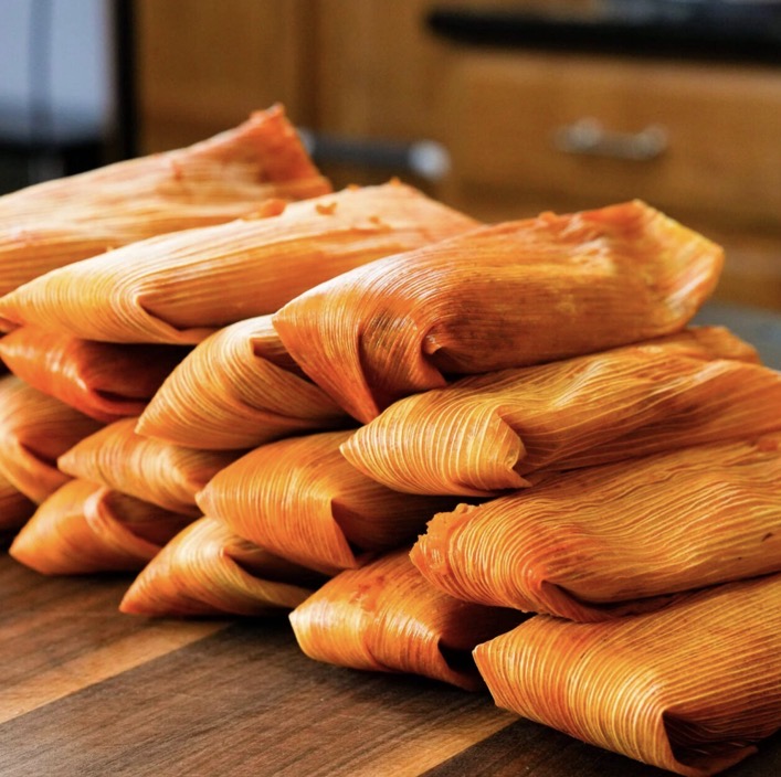 Stack of freshly steamed pork tamales in corn husks