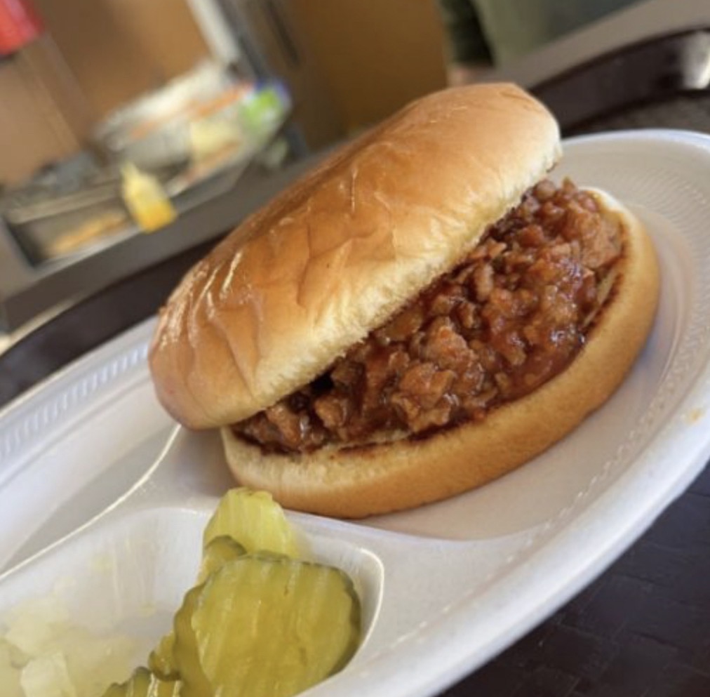 Chopped BBQ beef sandwich on a bun served with pickles
