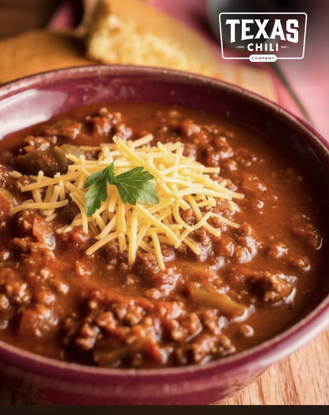 Bowl of Texas chili topped with shredded cheddar