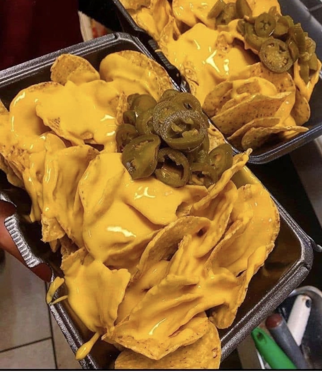 Trays of nacho chips smothered in cheddar cheese sauce with jalapeños
